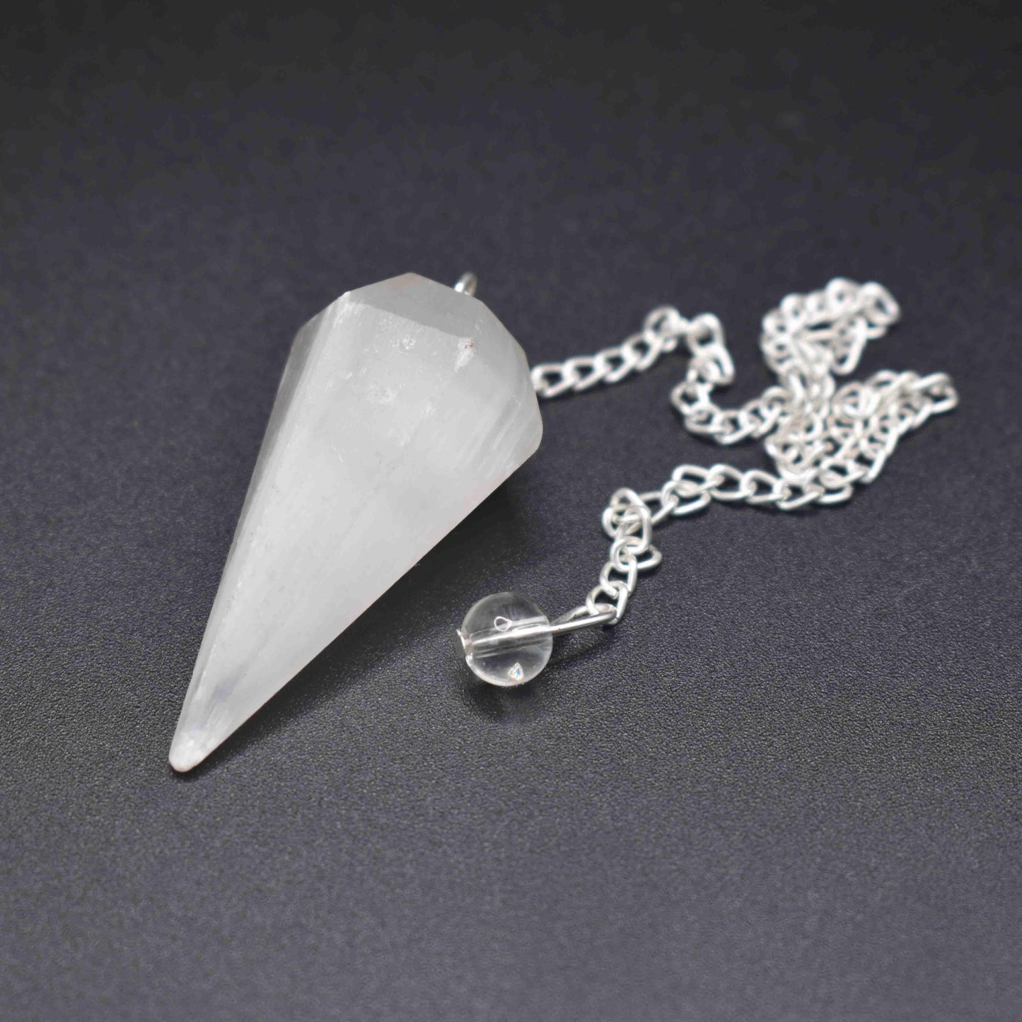 Selenite pendulum on black backgound front angle