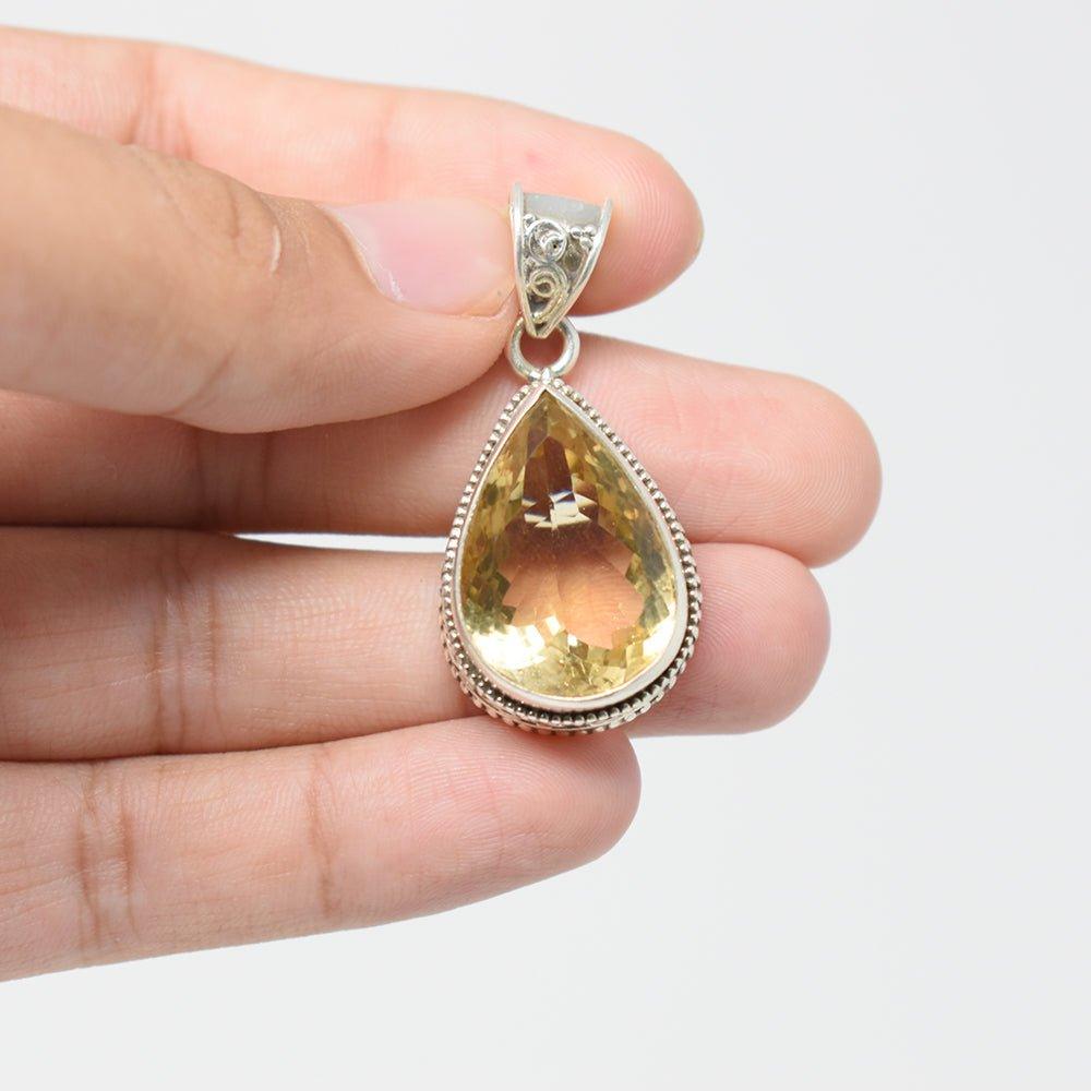 925 Sterling Silver Citrine pear shaped yellowish color Pendant in hand on skin colored and white background